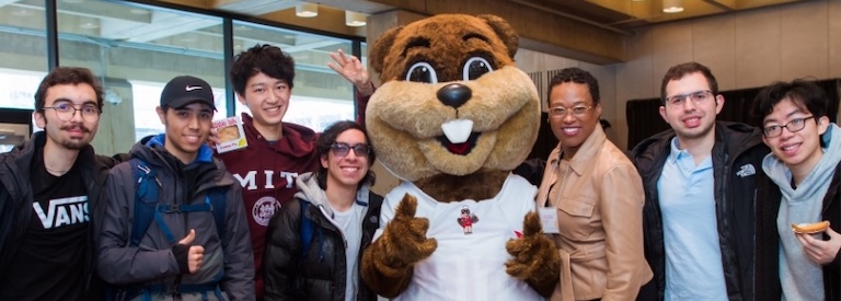 A group of students pose with Melissa Nobles and Tim the Beaver in Lobby 13